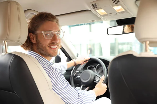 Aantrekkelijke jonge man rijden zijn luxe auto, uitzicht vanaf achterbank — Stockfoto