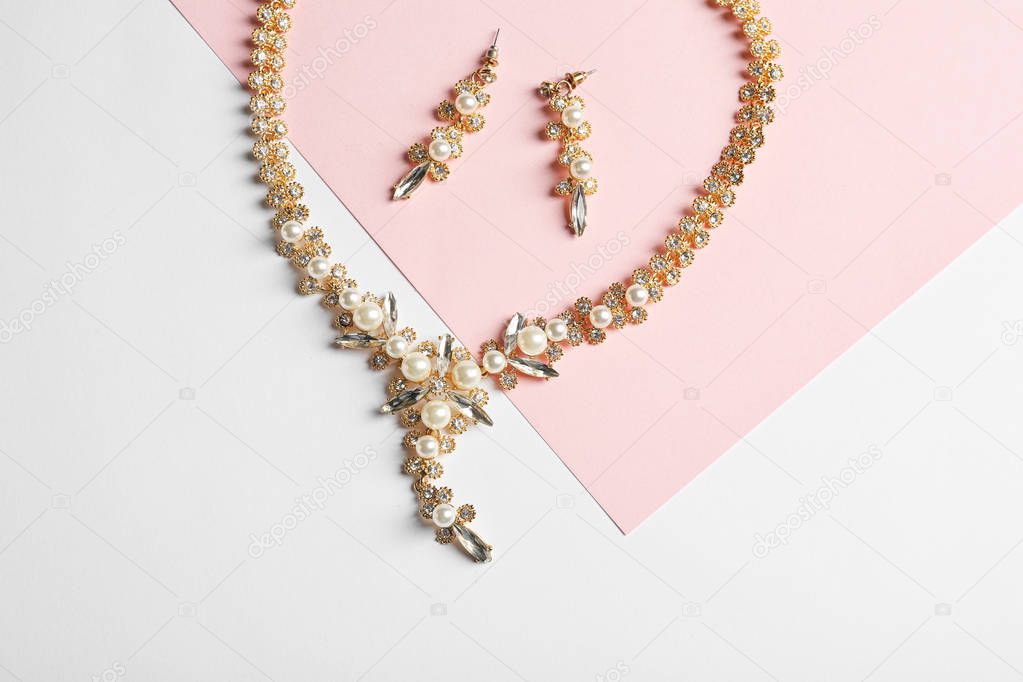 Set of elegant jewelry on color background, top view