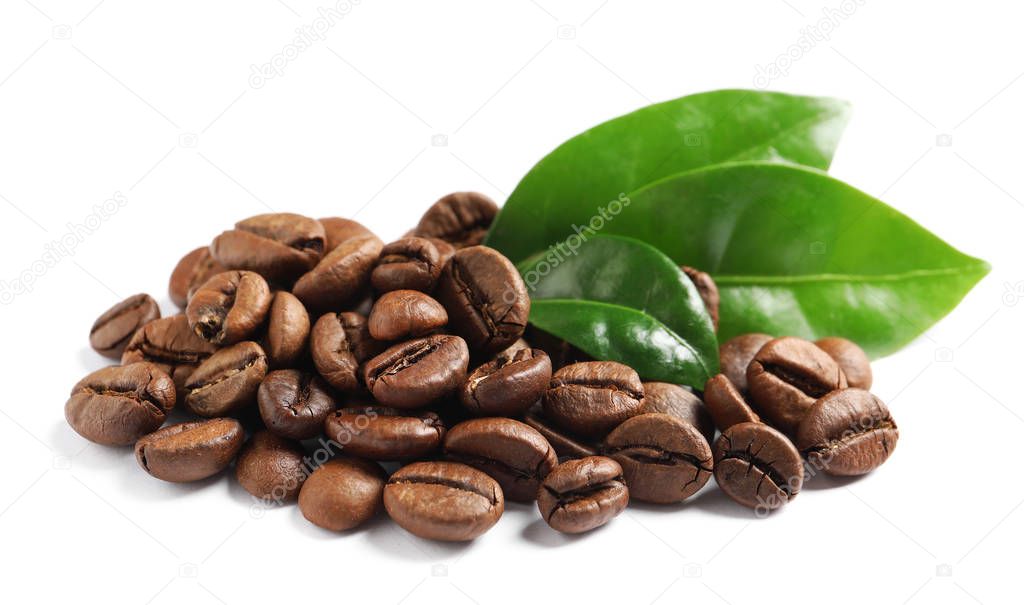 Roasted coffee beans and fresh green leaves on white background