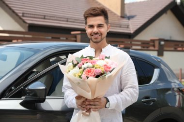 Araba açık havada güzel çiçek buket ile genç yakışıklı adam