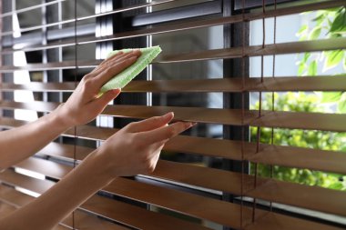 Pencereyi silen kadın içeride bezle, yakın çekim. Metin için alan