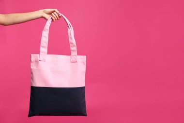 Pembe arka planda Tekstil çantası tutan genç kadın, kapatmak