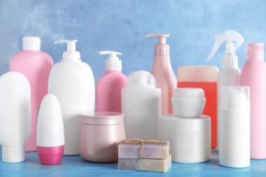 Mavi arka plana karşı ahşap masada farklı vücut bakım ürünleri