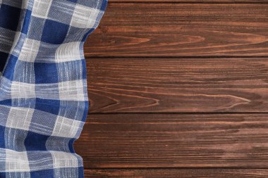 Ahşap arka planda mavi ekose mutfak havlusu, üst görünüm. Metin alanı
