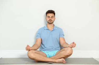 Genç adam egzersiz Zen Yoga yakın duvar kapalı