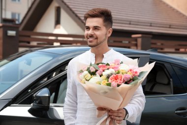 Araba açık havada güzel çiçek buket ile genç yakışıklı adam