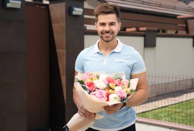 Güzel çiçek buket açık havada Genç yakışıklı adam
