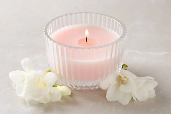 Lit vela e belas flores na mesa de mármore cinza — Fotografia de Stock