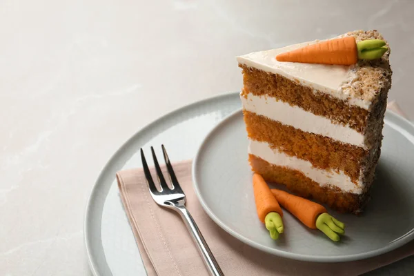 Piece of sweet carrot cake with delicious cream on light table, space for text