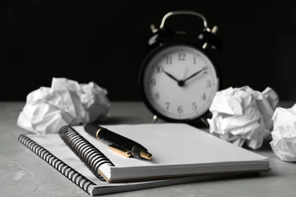 Notebooklar, gri masada kırışık Kağıt topları ve çalar saat — Stok fotoğraf
