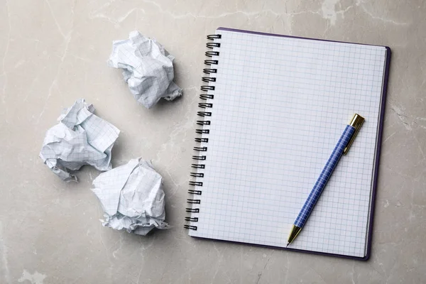 Notebook vazio com caneta e bolas de papel amassadas em mesa de mármore cinza, flat lay. Espaço para texto — Fotografia de Stock