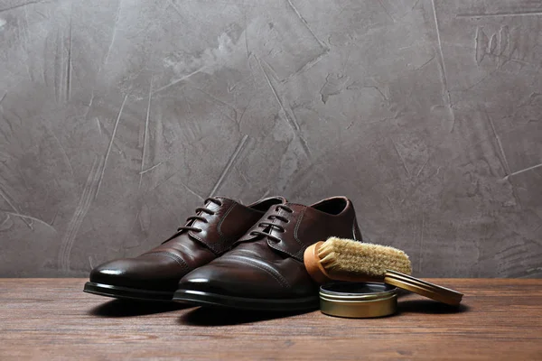 Leather footwear and shoe shine kit on wooden surface, space for text