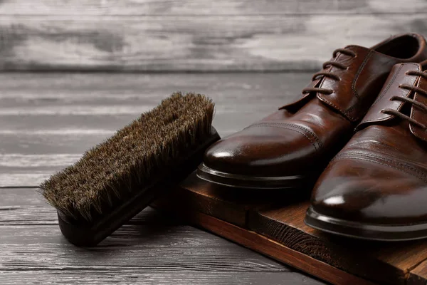 Heren leren schoenen en poets borstel op grijze tafel — Stockfoto