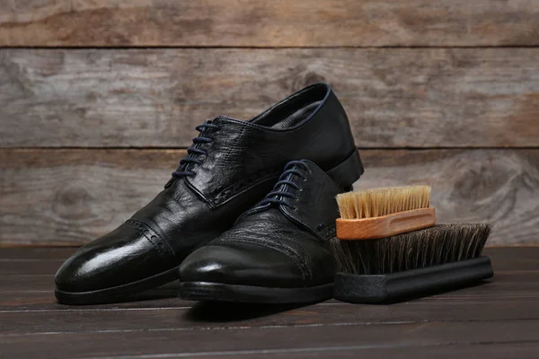 Heren leren schoenen en reinigingsborstels op houten tafel — Stockfoto