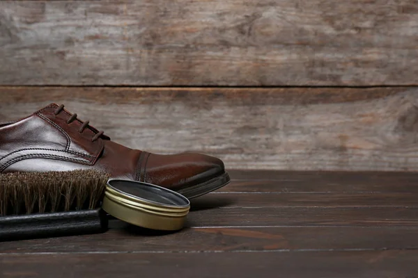 Footwear and shoe shine kit on wooden table, space for text