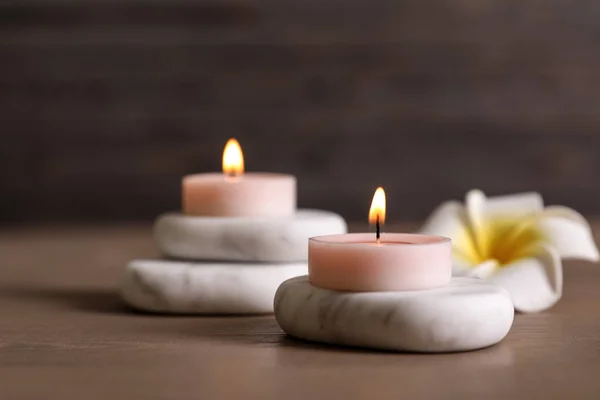 Состав спа-камней, цветов и горящих свечей на деревянном столе — стоковое фото
