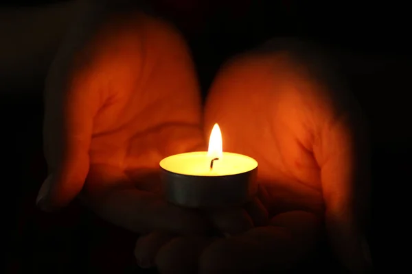 Woman holding burning candle in darkness, closeup — Stock Photo, Image