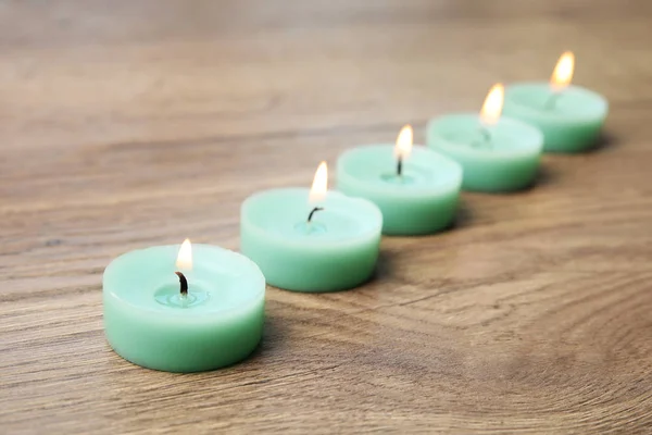 Hořící tyrkysové dekorativní svíčky na dřevěném stole — Stock fotografie