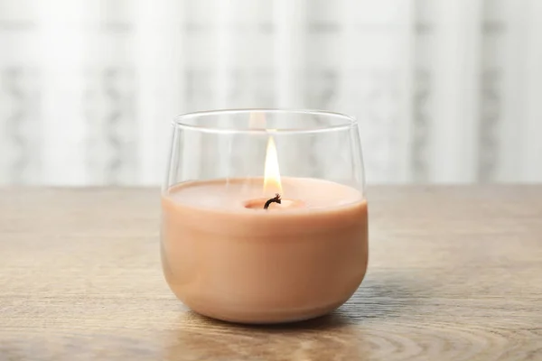 Hořící svíčka ve skleněném držáku na dřevěném stole — Stock fotografie