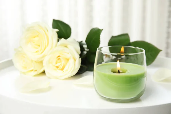 Burning candle in glass holder and roses on white table, space for text — Stock Photo, Image