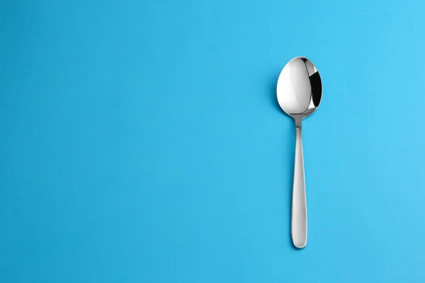 Pulire cucchiaio da tavola vuoto su sfondo blu, vista dall'alto. Spazio per testo — Foto Stock