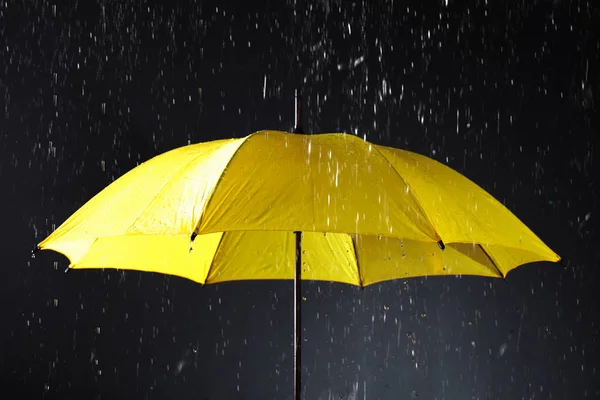 Guarda-chuva brilhante sob chuva no fundo escuro — Fotografia de Stock