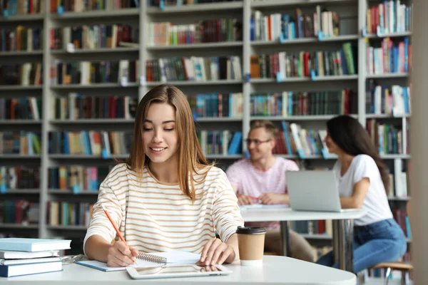 Молодая женщина учится за столом в библиотеке — стоковое фото