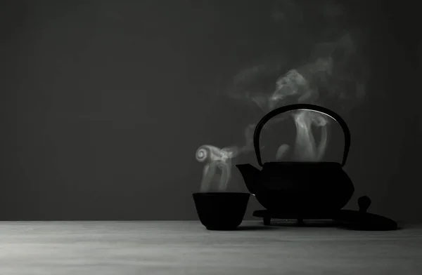 Восточный чайник и чашка на столе на сером фоне, пространство для текста — стоковое фото