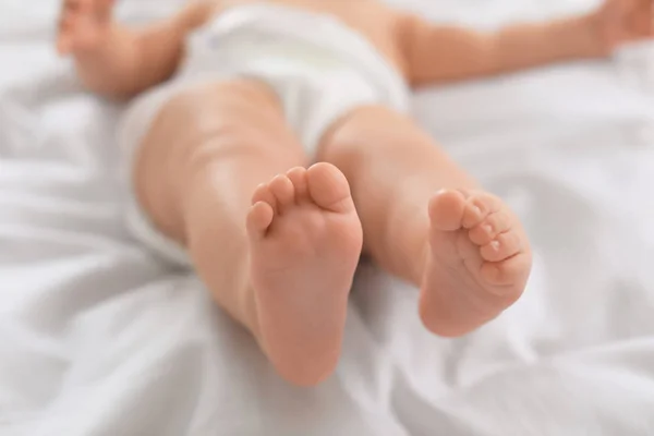 Sevimli küçük bebek yatakta yatan, bacaklar closeup — Stok fotoğraf