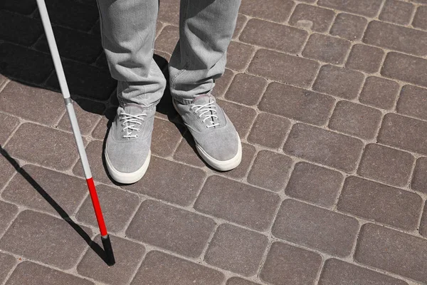 Blind person with cane walking outdoors, closeup. Space for text