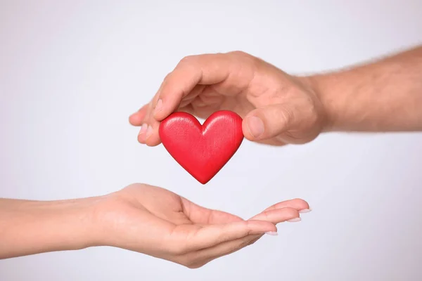 Man ger rött hjärta till kvinna på vit bakgrund, närbild. Donation begrepp — Stockfoto