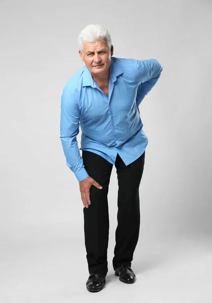 Volledige lengte portret van senior man met knieproblemen op grijze achtergrond — Stockfoto