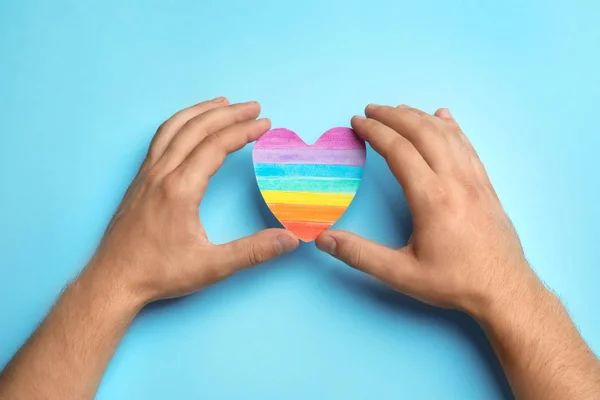 Man with rainbow heart on blue background, top view. Gay symbol — Stock Photo, Image