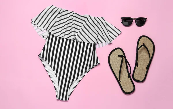 Composizione flat lay con costume da bagno a righe e accessori da spiaggia su sfondo rosa — Foto Stock