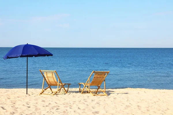 Κενές ξύλινες ξαπλώστρες και ομπρέλα στην αμμώδη ακτή. Αξεσουάρ παραλίας — Φωτογραφία Αρχείου
