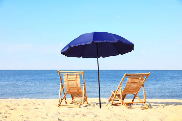 Chaises longues en bois vides et parasol sur le rivage sablonneux. Accessoires de plage — Photo