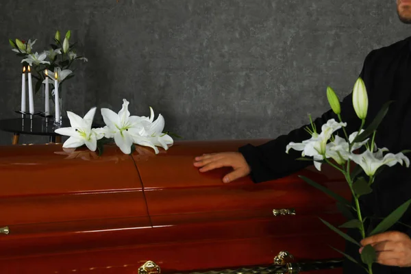 Молодий чоловік з білими ліліями біля коробки в похоронному будинку, крупним планом — стокове фото