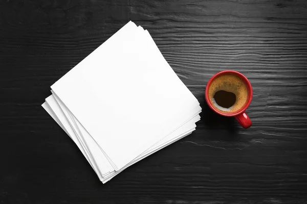 Blanco papieren vellen voor brochure en kopje koffie op zwarte houten achtergrond, platte lag. Mock up — Stockfoto