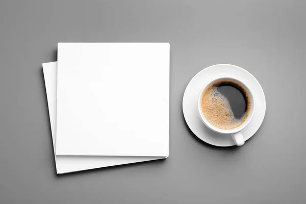 Blanco papieren vellen voor brochure en kopje koffie op grijze achtergrond, platte lay. Mock up — Stockfoto