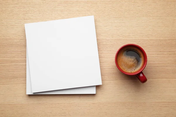 Blanco papieren vellen voor brochure en kopje koffie op houten achtergrond, platte lag. Mock up — Stockfoto
