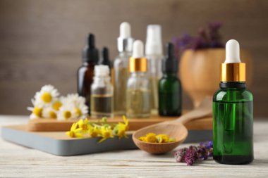 Farklı uçucu yağlar ve ahşap masa üzerinde yaban çiçekleri şişeler, metin için alan