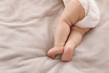 Yatakta yatan sevimli küçük bebek, bacakların çekim. Metin alanı