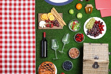 Yeşil çim üzerinde piknik sepeti ve ürünleri ile düz yatıyordu kompozisyon