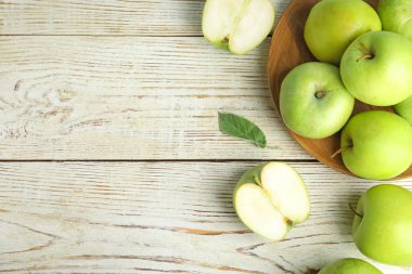 Düz beyaz ahşap masa üzerinde taze olgun yeşil elma bileşimi yatıyordu, metin için alan