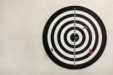 Hafif taş arka planda renk okları ile dart tahtası, üst görünüm. Metin alanı