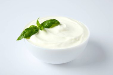 Beyaz arka plan üzerinde fesleğen ile taze ekşi krema Kase