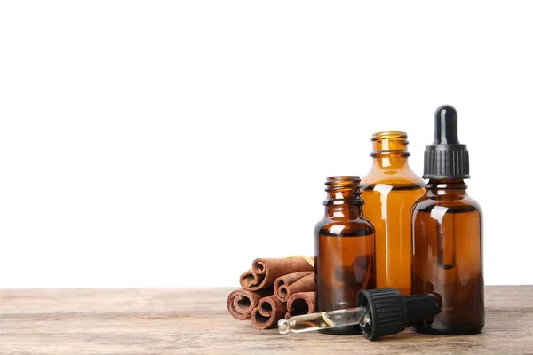 Láhve esenciových olejů a skošových tyčí na dřevěném stole proti Bílému podkladu. Místo pro text — Stock fotografie
