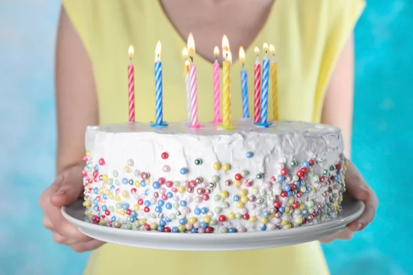 Жінка тримає торт на день народження з палаючими свічками на світло-блакитному фоні, крупним планом — стокове фото