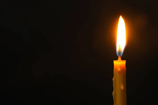 Burning candle on dark background, space for text. Symbol of sorrow