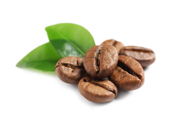 Geröstete Kaffeebohnen und frische grüne Blätter auf weißem Hintergrund — Stockfoto